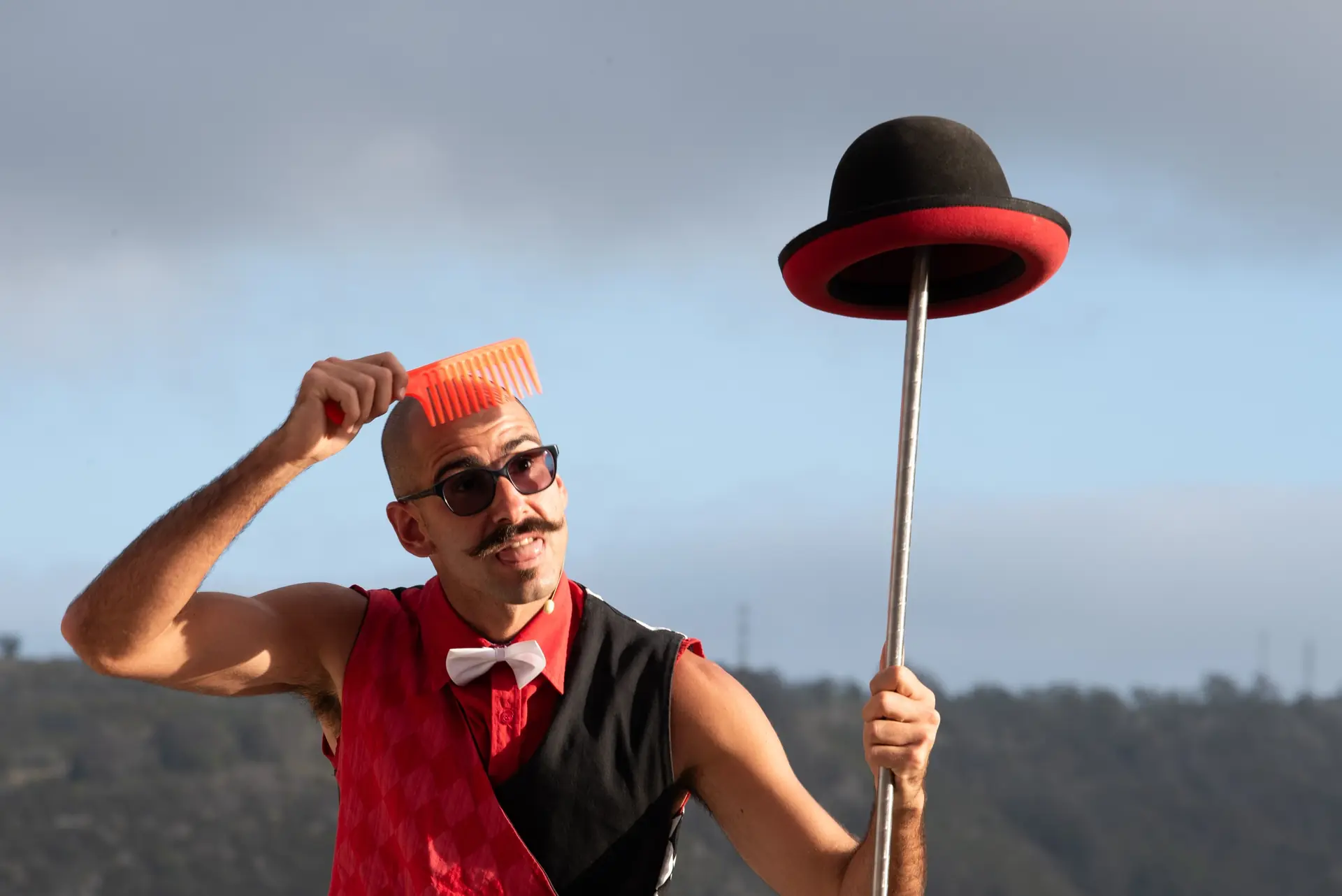 Tadeo combing his head with a hat on a stick